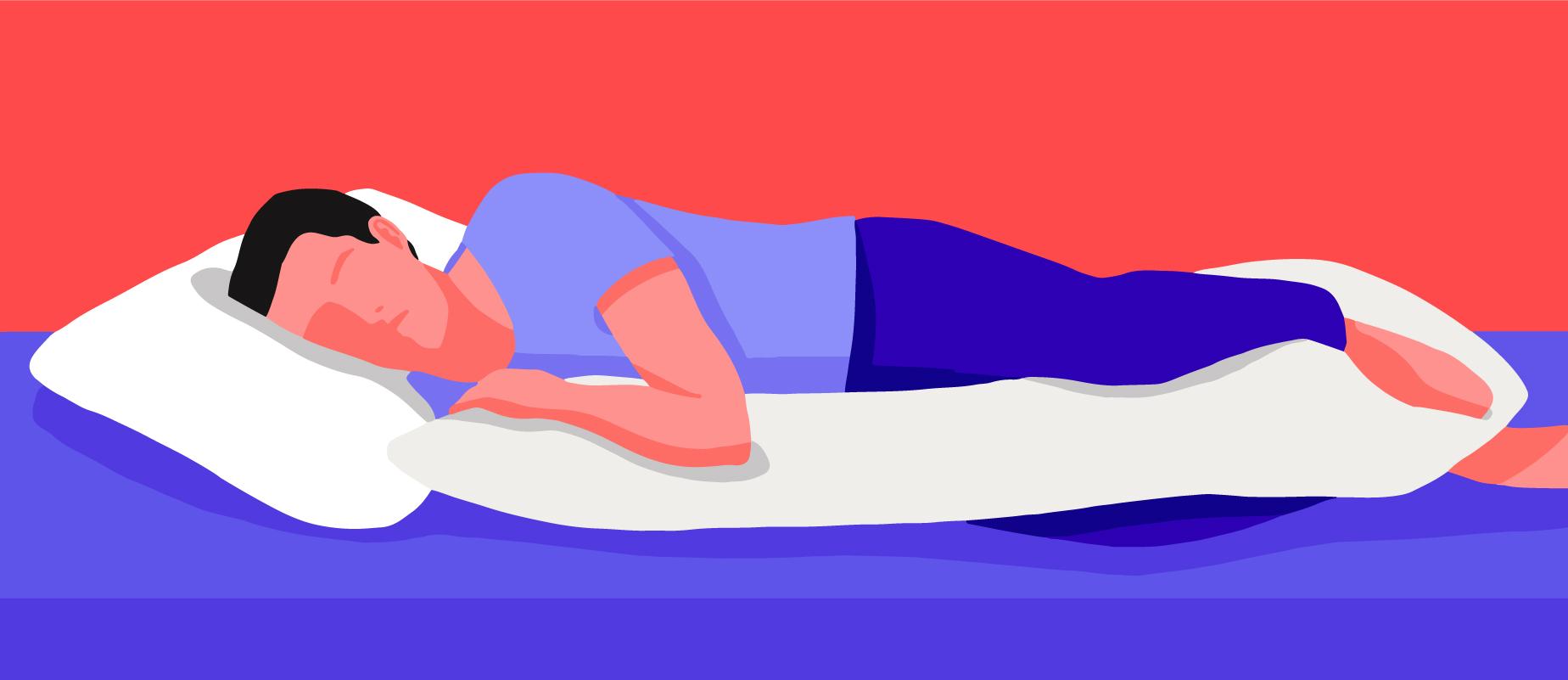 A man on a bed sleeping on his side with a body pillow.