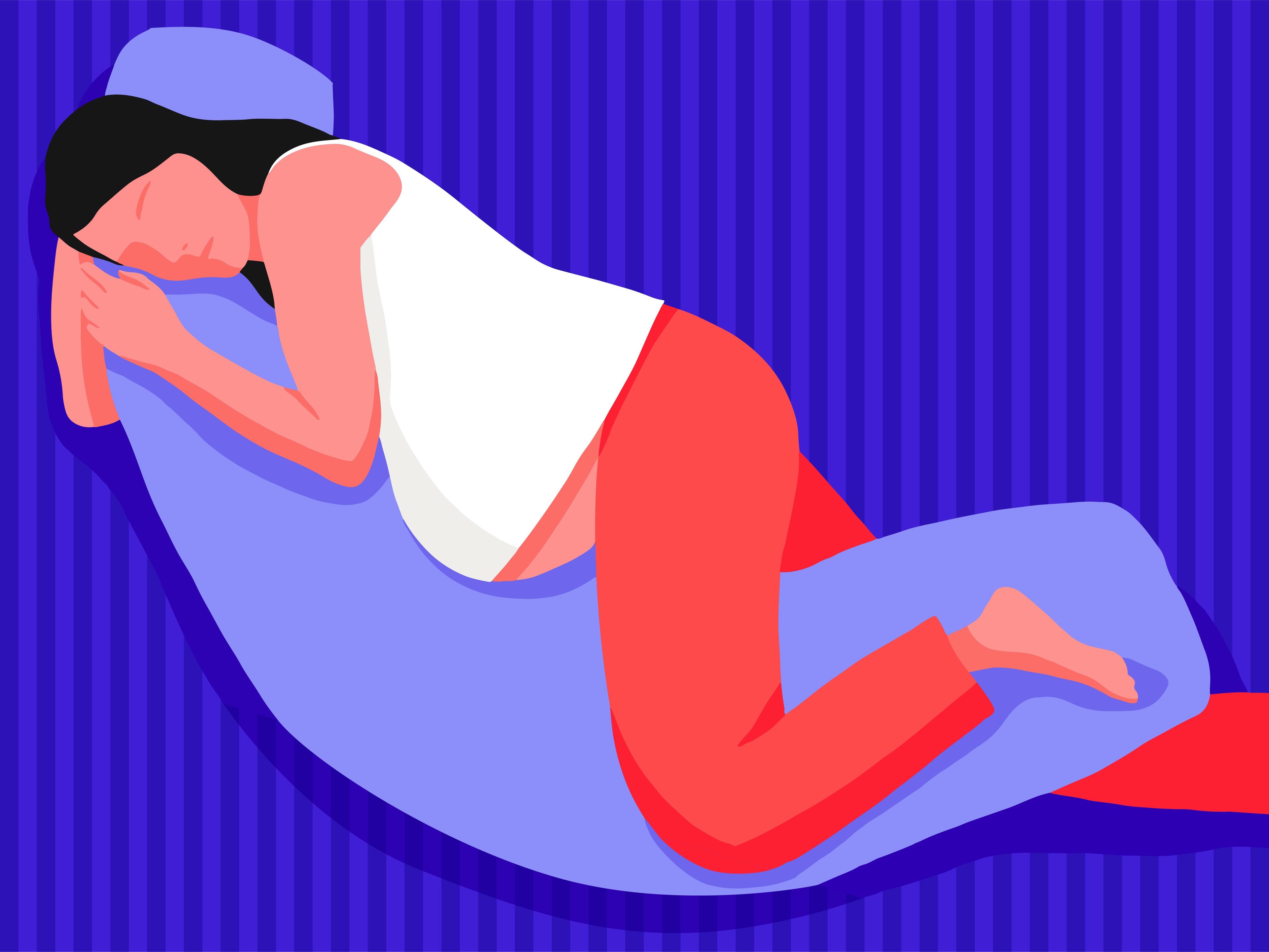 A pregnant woman sleeping on her side using a maternity pillow.