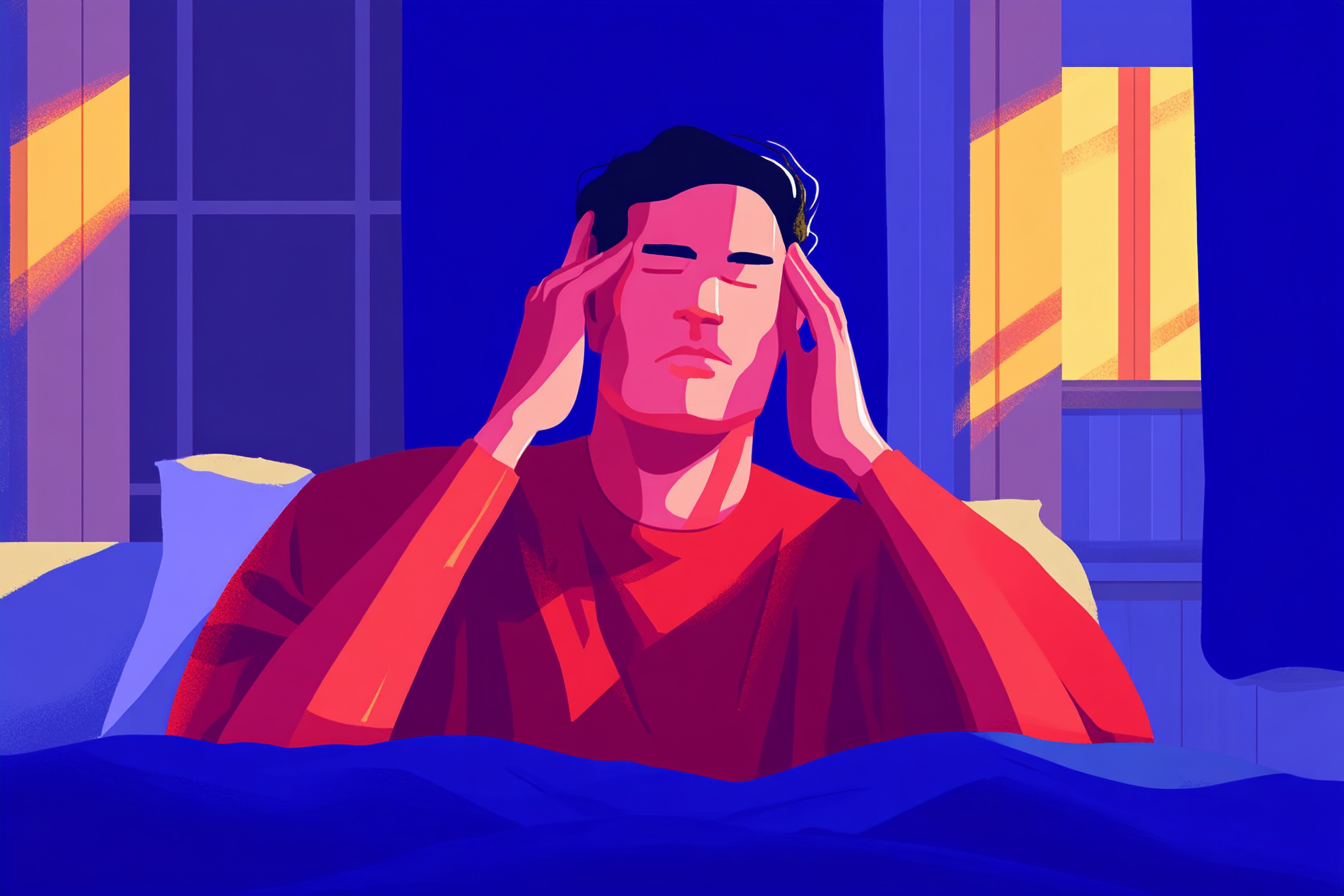 A man suffering from a morning headache, lying in bed and massaging his temples.