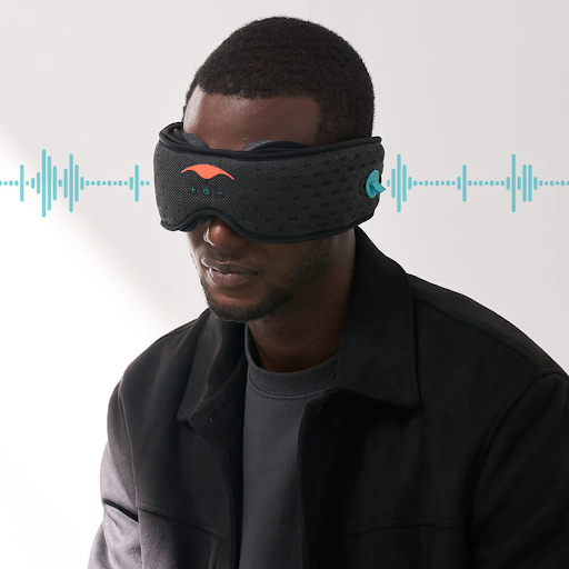 A man listening to music on a sleep mask with headphones. Blue sound waves emanate from either side of his head.